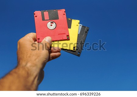 Diskettes in man hand over blue sky