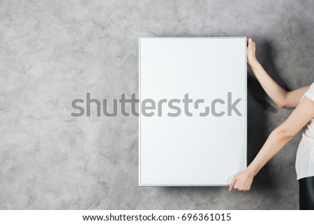 Woman hands holding empty billboard on concrete wall background. Mock up