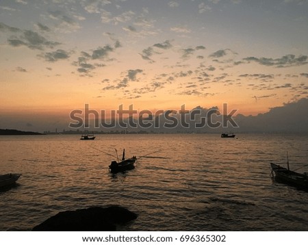 Silhouette of boats on the sea while sunrise, orange light of sun reflect on the sea. This view make human alone and relax together. Blur picture.