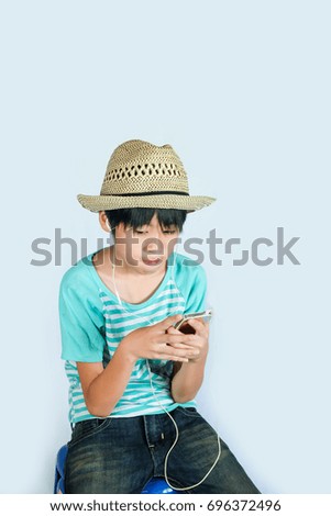 Cute boy use mobile phone for listen to music.Asia kid play mobile phone.blue background.