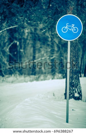 Picture of winter day with trees with road sign of bicycle path in frost. Toned photo