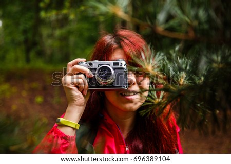 Picture of brunette with camera in woods at summer afternoon