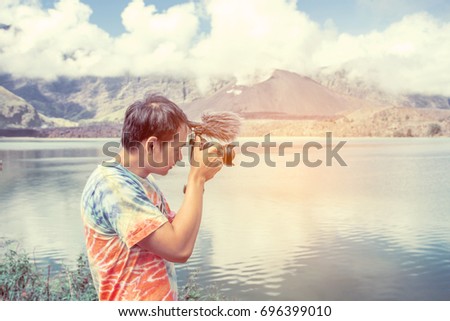 Man photographer and camera taking photo at Rinjani, Indonesia. Travel Lifestyle hobby concept adventure active vacations outdoor.