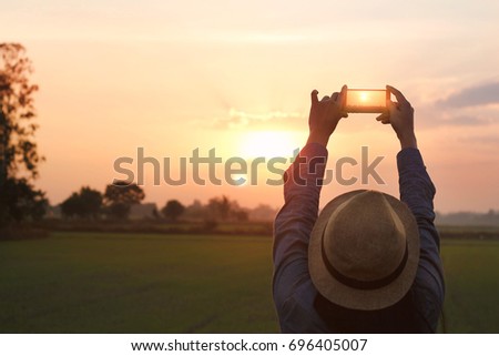 Tourist woman taking a photo with smartphone on sunset nature background 