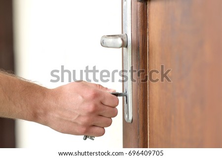 Closeup photo of male hand puts the key in the keyhole.
