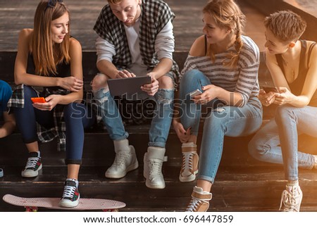 Group of friends having fun at the cafe and looking at smart phone. Man showing something to his friends sitting
