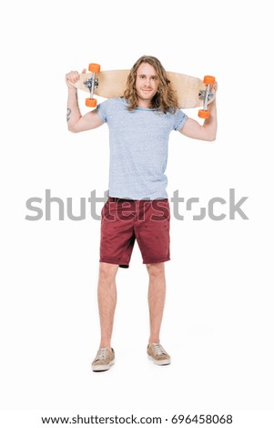 handsome young long haired man holding skateboard and smiling at camera isolated on white 