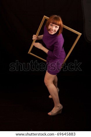 a young adult woman trying to climb through a picture frame