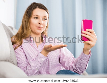 Smiling female using her phone and taking photos at home