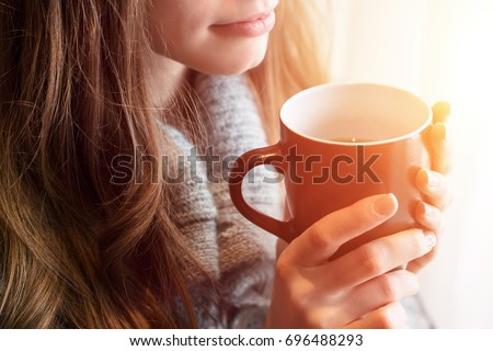 Tea time. Beautiful blonde woman holding ceramic cup of tea or coffee enjoy closeup. Looking at window and drink tea. Good morning with tea. Selective focus. Pretty young girl relaxing. Happy concept.