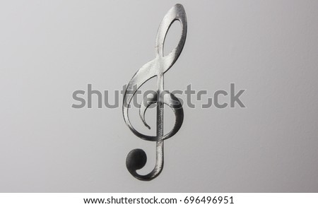 Metal treble clef on a white wall
