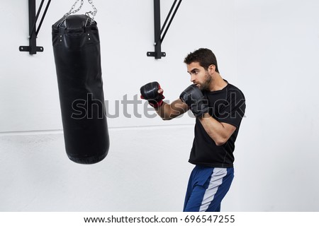 Guy boxing with punch bag in gym