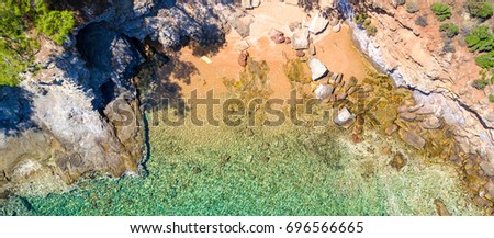 Aerial view of sandy beach with rocks and clear turquoise water