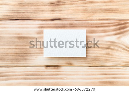 Closeup mockup of white blank horizontal business card at light natural wooden background.