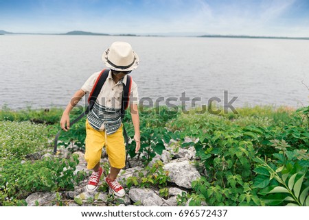 asian boy tourist with a backpack standing  at the cliff by the lagoon  