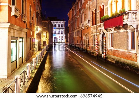 Long exposure photo of Venice at night with traces of floating boats on water.