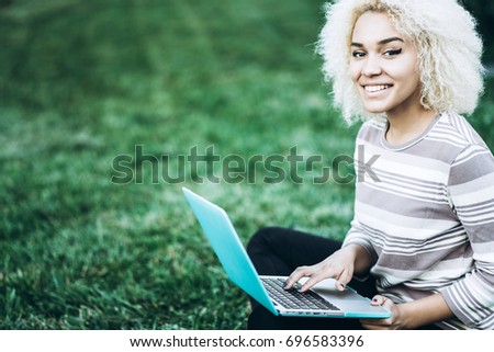 Student studying outdoors on grass with the laptop
