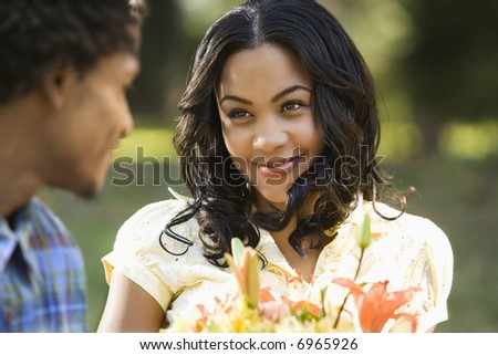 Woman holding flower bouquet smiling at man.