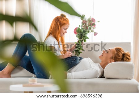 side view of little girl presenting bouquet of flowers to mother at home, happy mother day concept