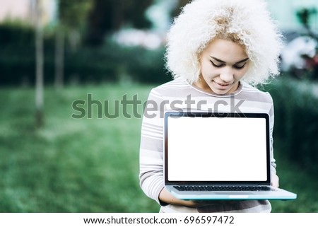Cheerful young student girl holds a laptop with a white screen