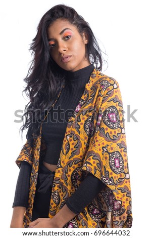 Semi profile of girl looking at the camera. Afro descendant woman wears black and yellow clothing. She is Brazilian. Makeup colored. Fashion. Style. Personality.