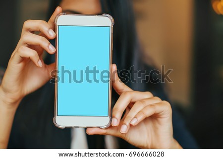 A phone with a blank green screen being held by an Indian woman 