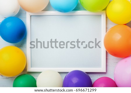Colorful balloons and white frame on blue wooden table top view. Mockup for planning birthday or party. Flat lay style. Copy space for text. Festive greeting background.