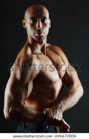 athletic muscular man shows his biceps studio shot over dark background