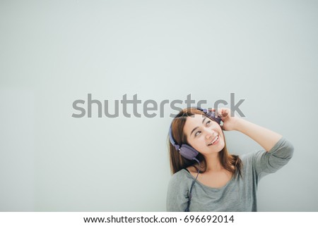 Lifestyle concept - a picture of a beautiful Asian girl listening to music through purple headphones. White background Copy space