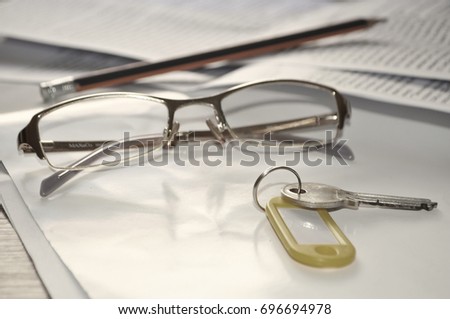 Key, glasses and pencil over documents