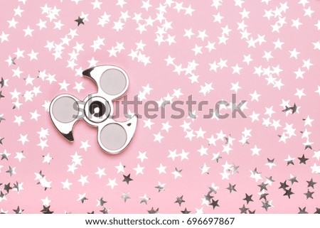 Silvery spinner on a pink background with stars. The concept of trend toys, dreams, fashion