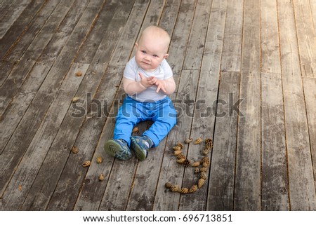 The child is sitting on wooden floor and smiling
