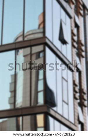 Blurred background: Geometrical texture of shining office windows with sky reflection