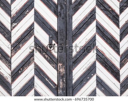 Old wooden gate in black and white stripes. Wooden contrasting background.