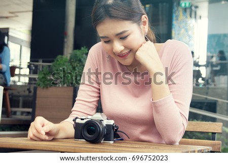 pretty cool young Asian woman with retro film camera or mirrorless camera in modern garden open mall.young woman holding mirrorless camera in vintage tone