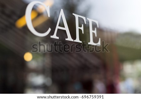 Inscription Cafe on the window glass at cafe. Selective focus on Cafe letters with blurred interior background