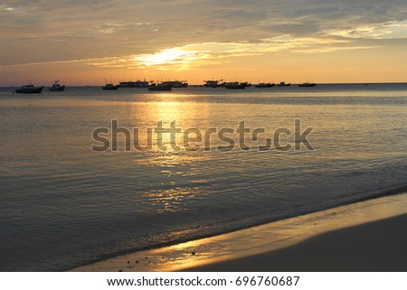Fishing boats at a deserted beach on a sunset background