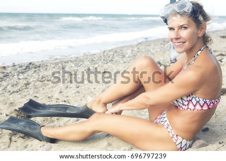 portrait of beautiful blond woman with swimming goggles and flippers on the beach