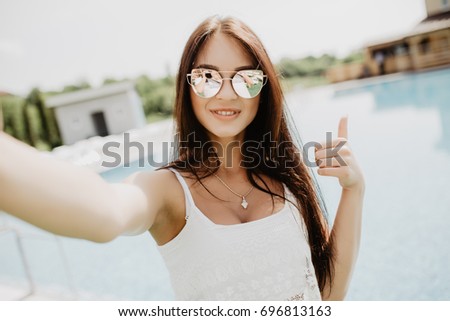 Portrait of beautiful girl taking a selfie at the swimming pool.
