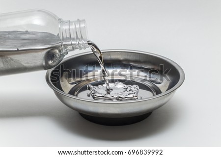 Pouring elemental mercury in a steel bowl Royalty-Free Stock Photo #696839992
