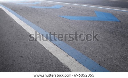 Blue navigation arrow and White and blue double dividing line on asphalt road background,Good heart always leads to the right way.