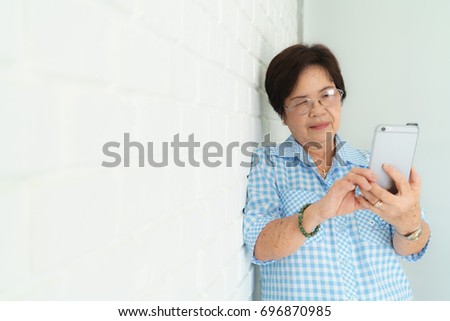 Old Asian Woman with a glasses play Smartphone on white Background