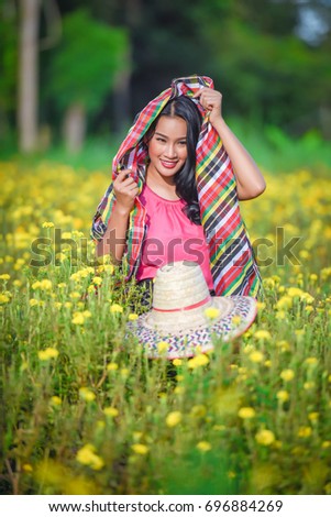 Beautiful girl collects flowers in the field, in the evening on a sunset. A woman collects marigold flowers.