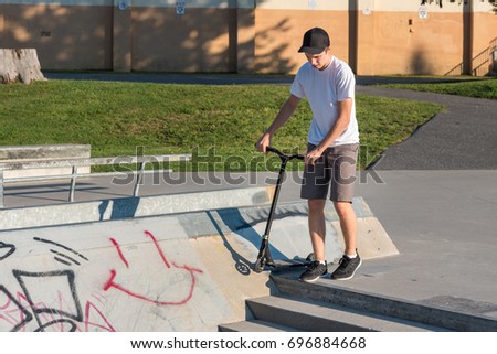 Teenager riding a kick scooter at a skate park.