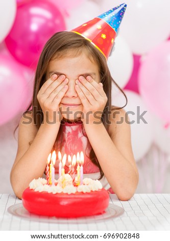 Girl with birthday cake closed her eyes with her hands making a wish