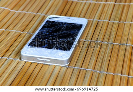 mobile smartphone with broken screen on wooden background.
