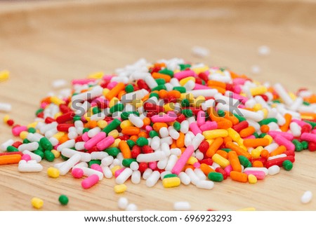 colorful rainbow sprinkles on wooden plate