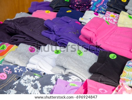 A collection of colorful kids' clothing with prices arranged on a table at a garage sale Royalty-Free Stock Photo #696924847