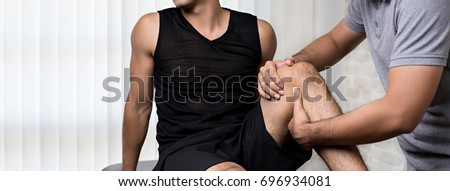 Therapist treating injured knee of athlete male patient in clinic - sport physical therapy concept,panoramic banner Royalty-Free Stock Photo #696934081