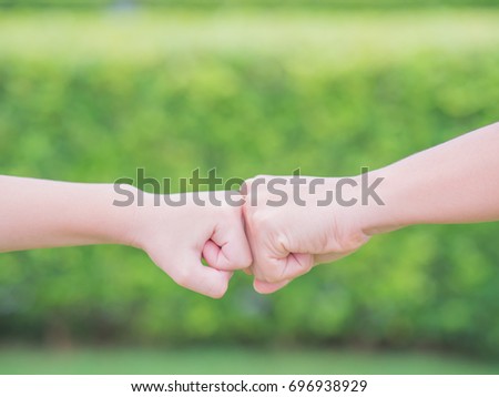 Closeup mother and son are fist bumping in green background. People, charity and family concept.